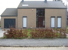 Porte de garage sectionnelle foncée. Volets roulants sur les fenêtres hautes et étroites.